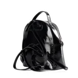 Mochila negra de charol con logo circular en relieve en la parte superior. Tiene un asa corta en la parte superior y correas regulables. Cuenta con un bolsillo externo con cierre y dos bolsillos internos abiertos y uno con cierre.