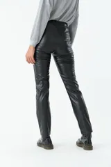 Pantalón negro de cuero sintético, tiro medio y corte recto.