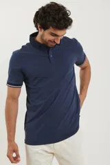 Chomba blanca de piqué con cuello y puños en azul marino.