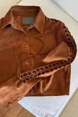 Camisa color caramelo claro de gamuza, con cuello clásico, calados artesanales en las mangas y cierre frontal con botones.