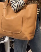 Bolso tote negro de cuero vacuno con costuras a la vista.