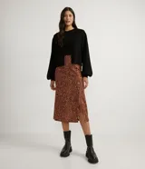 Chaqueta corta de punto color negro, con escote en V, manga larga abullonada, sisa desplazada, abotonado frontal total con botones forrados y puños acanalados.