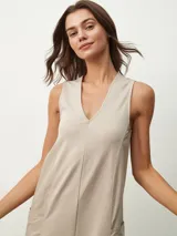 Mono largo color beige, de corte holgado, con cuello redondo y mangas cortas. Presenta bolsillos laterales y detalle de costuras verticales en el frente.