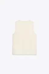 Chaleco color crema de punto con cuello redondo y sisa. Tiene botones metálicos dorados en los laterales.
