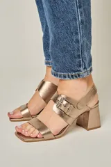 Sandalias de cuero color champagne, con punta cuadrada, tira ancha sobre el empeine con hebilla metálica, tira trasera con elástico y taco bloque de 7 cm.