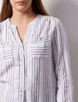 Blusa de lino a rayas verticales blancas y grises, marca Zac & Rachel. Tiene cuello a la base, escote en V y abertura central con botones. Cuenta con dos bolsillos en el pecho y mangas largas regulables con presilla y botón.