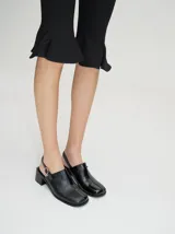 Zapatos tipo mocasín de cuero vacuno negro, con taco de madera de 5cm y correa trasera ajustable.