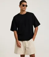 Bermuda masculina confeccionada en tejido de tricolina con estampa de rayas rústicas, cintura elástica con cordón ajustable y bolsillo.