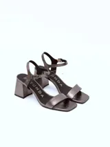 Sandalias de cuero charol negro con tira delgada sobre los dedos, pulsera con hebilla al tobillo y tacón cuadrado.