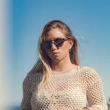 Lentes de sol redondos con marco azul translúcido y lentes grises degradé.