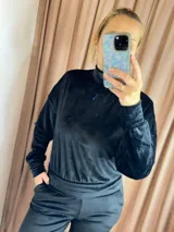 Conjunto deportivo de terciopelo negro, compuesto por un buzo de cuello alto con mangas largas y puños elásticos, y un pantalón jogger con cintura elástica.