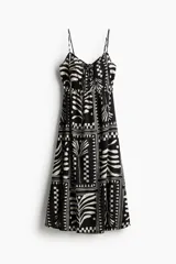 Vestido midi de algodón con estampado geométrico en blanco y negro. Tiene breteles finos ajustables, escote corazón con abertura y tiras para atar en el busto, elástico bajo el busto y falda con leve vuelo.