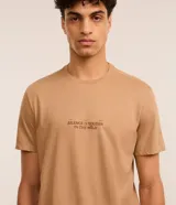 Remera color beige de algodón, corte comfort, con cuello redondo y mangas cortas. Presenta estampa de montañas y texto "Silence is louder in the wild".