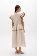 Vestido midi amarillo de lino, con volados en las mangas y detalle de volados y botones a lo largo del frente. Presenta un corte con talle marcado y falda escalonada.