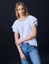 Blusa blanca texturada de poliéster, rayón y elastano, con mangas cortas con volados en capas y aplique de puntilla.