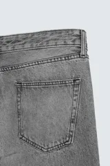 Pantalón de jean celeste de corte flare, con tiro medio, cinco bolsillos, cierre frontal con cremallera y botón, y bajo con acabado irregular.