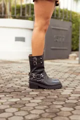 Bota de cuero negra con caña media, hebillas metálicas y suela track.