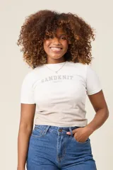 Remera blanca de algodón con mangas cortas y cuello redondo. Estampado frontal con el texto 'SANDKNIT SINCE 1981' en color gris. Diseño con efecto degradado en la parte inferior.