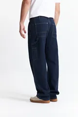 Pantalón jean celeste de corte carpenter, tiro medio, con presillas para cinturón y bolsillos laterales.
