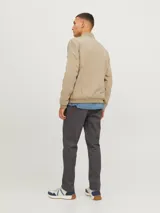 Campera bomber color beige con cuello de béisbol, cierre con cremallera, bolsillos frontales con cremallera y bolsillo en la manga.