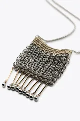 Bolso mini tipo saco confeccionado con hilo metalizado y arandelas en forma de malla. Detalle de aplicaciones metálicas de diferentes formas. Asa tipo cordón metálico.