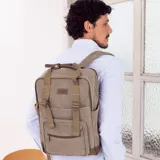 Mochila de tela canvas color marrón con detalles en cuero. Tiene compartimento principal con cierre y espacio interior para termo, mate y notebook.