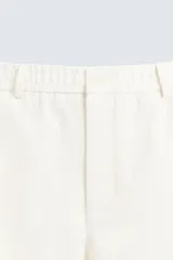 Pantalón de vestir color blanco hueso, de corte recto y tiro medio, con cintura elástica y cierre frontal de botón y cremallera. Presenta bolsillos frontales y bolsillos traseros de vivo.