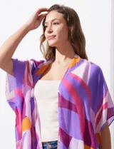 Kimono tejido con estampado geométrico en tonos verde, amarillo y marrón. Tiene mangas amplias estilo japonés y terminación de ruedo con borlas.