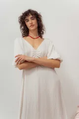 Vestido midi color crudo, de corte suelto, con escote en V y mangas abullonadas.