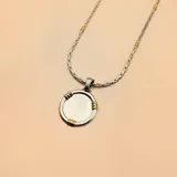 Collar con cadena de eslabones plateada con detalles dorados y dije circular plateado con apliques dorados.