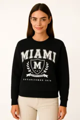 Buzo negro de cuello redondo y manga larga, con estampado frontal de la palabra "PARIS" en color lila con borde blanco.