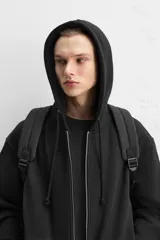 Mochila negra con acabado engomado, compartimento principal con cierre de cremallera, bolsillo interior con cierre, bolsillo frontal con cierre, bolsillos laterales planos, respaldo acolchado con sujeción para equipaje, asa de mano y dos asas de hombro ajustables y acolchadas.