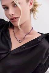 Collar con cadena de piedras facetadas color azul y dije central en forma de corazón con detalle floral.