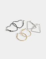 Set de tres pares de aros con cierre catalán: un par de argollas doradas, un par de aros trapezoidales plateados y un par de aros con forma de corazón negros.
