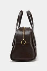 Bolso de mano y bandolera color marrón oscuro, con forma redondeada y doble asa superior. Presenta cierre principal de cremallera y un bolsillo interior con cierre.