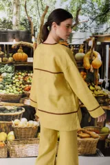 Blusa color crudo de lino con cuello en V y ribete marrón.