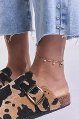 Zuecos con estampado de vaca en tonos camel y negro, con hebilla metálica ajustable y plantilla anatómica.