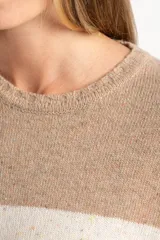Sweater de punto con diseño de rayas horizontales anchas, alternando color beige camel y blanco roto con motas de color. Presenta cuello redondo y puños y borde inferior acanalados.