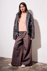 Pantalón de jean tiro medio, corte wide leg, confeccionado en tela de algodón con rayas verticales marrones y azules.