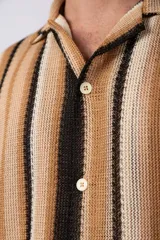 Camisa de manga corta con cuello clásico y botones frontales. Diseño con rayas verticales en tonos marrón, beige y negro.