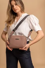 Bandolera pequeña de textura símil cuero color caramelo/marrón, con dos compartimentos principales con cierre. Correa ancha ajustable de tela negra con inscripción en relieve.