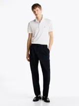 Chomba Tommy Hilfiger blanca con finas rayas horizontales celestes, corte regular, cuello clásico, tapeta de dos botones y logo bordado en el pecho.