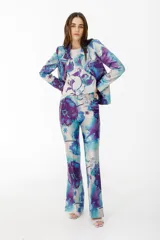 Pantalón de vestir con leve evasé y tajo en laterales, con estampado floral en tonos celeste, blanco y violeta.