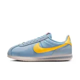 Championes Nike Cortez celestes con detalles en amarillo y suela blanca.