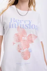 Remera blanca de algodón con cuello redondo y mangas cortas. Estampado frontal con la frase "Berry Infusion" en color lila y dibujo de frambuesas en color coral.
