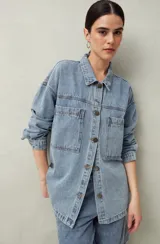 Sobrecamisa oversize de jean azul con cuello camisero, cierre frontal con botones, mangas largas y bolsillos de parche en el pecho.