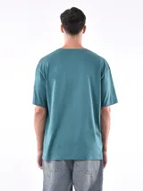 Remera gris de corte oversized, cuello redondo y mangas cortas. 