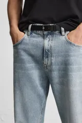 Pantalón de jean negro con efecto lavado, corte flare, cinco bolsillos, cierre frontal con cremallera y botón, y bajo con acabado irregular.
