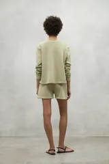 Buzo color verde claro, de corte clásico, con cuello redondo y puños acanalados. Confeccionado en 50% algodón reciclado y 50% algodón orgánico.