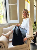 Bolso tipo tote bag negro de cuero, con costuras a la vista y manijas cortas.